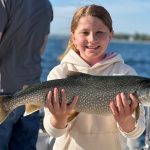 Young girl holding a lake trout caught on a Lake Michigan fishing charter near Traverse City