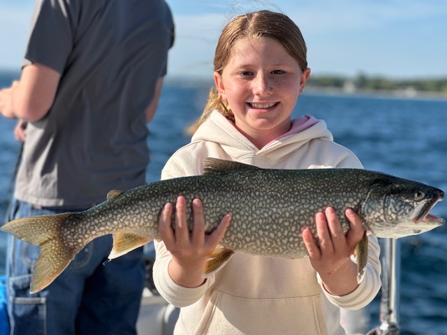 Young girl holding a lake trout caught on a Lake Michigan fishing charter near Traverse City