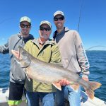 Anglers holding a large lake trout during a Traverse City fishing charter on West Grand Traverse Bay