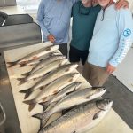 Guests displaying a catch of lake trout and salmon after a successful Traverse City fishing charter on West Grand Traverse Bay