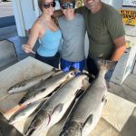 Family showing off four salmon and a lake trout after a successful Traverse City fishing charter on West Grand Traverse Bay.