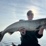 Woman holding a large salmon caught during a Traverse City fishing charter on West Grand Traverse Bay
