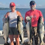 Couple holding four Lake Michigan salmon during a successful Traverse City fishing charter on West Grand Traverse Bay.