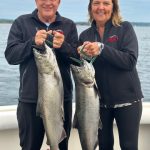 couple holding two Lake Michigan king salmon during a Traverse City fishing charter on West Grand Traverse Bay.
